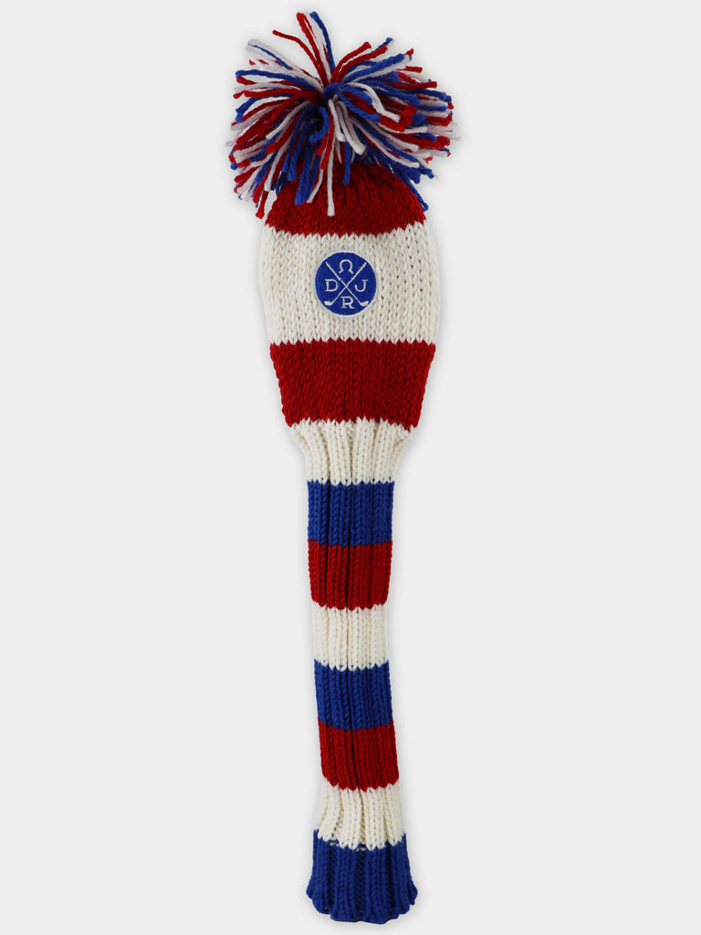 Red, white, and blue striped knit golf club head cover with a pompom top and embroidered crest.