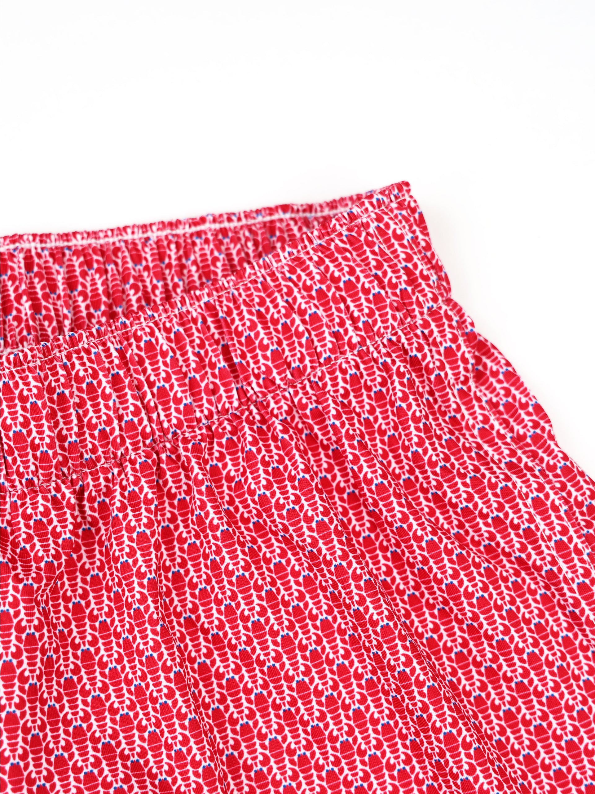 Red and white patterned fabric with a textured weave detail displayed against a neutral background.