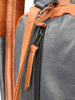 Close-up detail of a two-tone leather bag with tan straps and black body, showing hand-stitched seams and a dark zippered pocket.