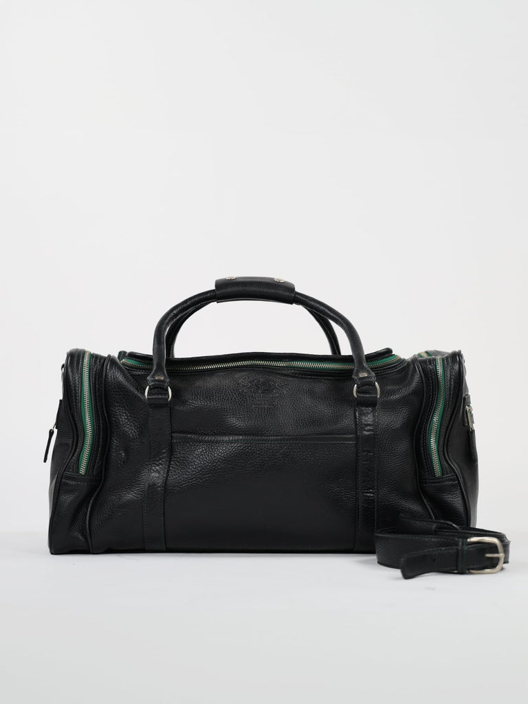 A black leather duffle bag is shown against a plain white background. It has green zippers, dual handles, and an adjustable shoulder strap, conveying a classic and functional design