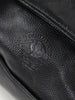 Close-up of a black leather duffel bag with an embossed logo featuring intricate detailing, creating a sleek and sophisticated look