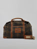 Vintage-style duffel bag with a plaid pattern, brown leather accents, sturdy handles, and a prominent leather patch, set against a plain background