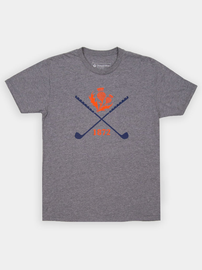 Gray T-shirt featuring blue crossed golf clubs and a red thistle design. The number "1872" is printed in red beneath the clubs, adding a vintage feel.