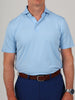 Man in a light blue polo shirt and dark blue pants, wearing a brown leather belt and silver watch, stands against a neutral background.