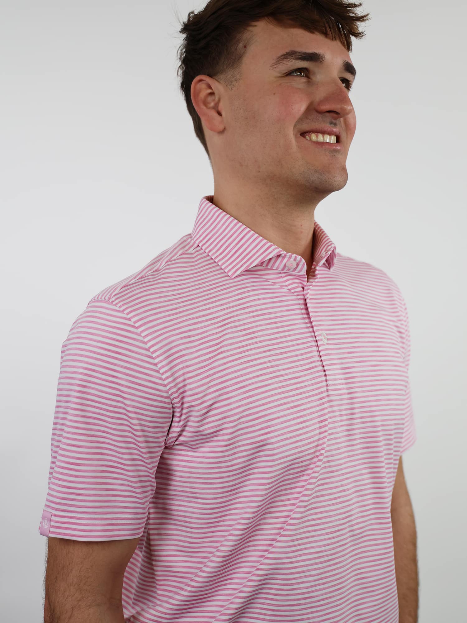 Smiling man in a pink and white striped polo shirt against a plain white background