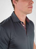 Man wearing a dark gray collared shirt with red-striped detail on the inside
