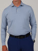 A person wearing a light blue long-sleeve polo shirt and navy pants is shown from the neck to knees. They have a black belt and a silver watch.