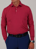 A person wearing a long-sleeve, dark red polo shirt and blue pants, with a black belt. Their right hand is in their pocket, and they wear a wristwatch.