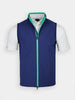 A navy blue vest with green trim over a white polo shirt on a mannequin. The vest features a vertical zipper and side pockets, creating a sporty look