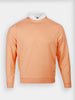 A peach-colored french terry crewneck sweater with long sleeves, featuring a white collared shirt underneath. The style is casual and neat, set against a plain white background.