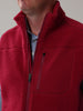 A person wearing a red fleece jacket with a high collar. The jacket has a zippered chest pocket and soft, textured fabric.