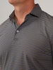A man is wearing a striped polo shirt with blue and yellow lines and is looking slightly upward.