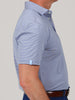A man wears a blue and yellow striped polo shirt with a small label on the sleeve. He's in profile with arms relaxed, conveying a casual tone.