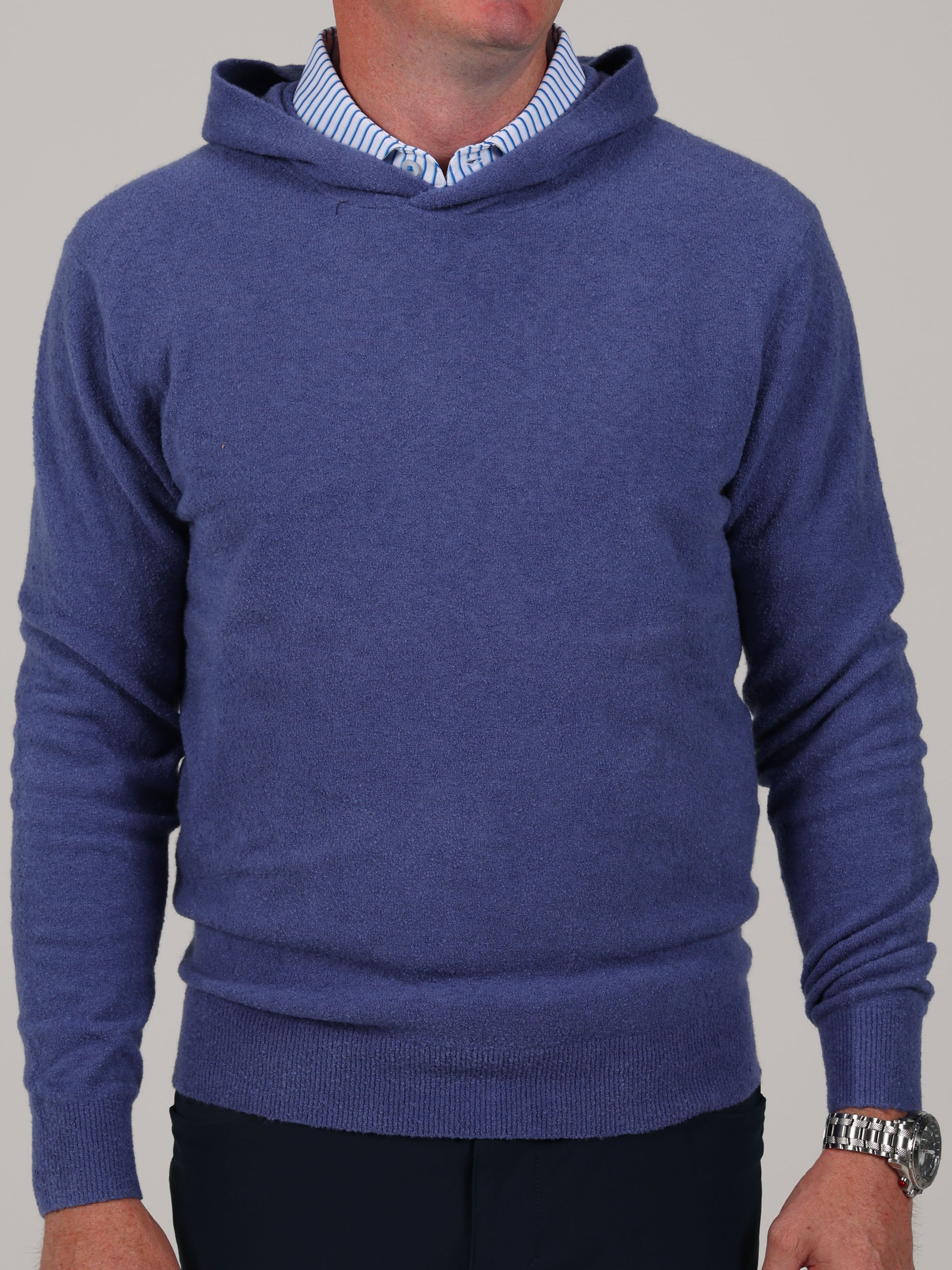 A denim blue bouclé hoodie featuring a rich cashmere blend fabric and adjustable hood.