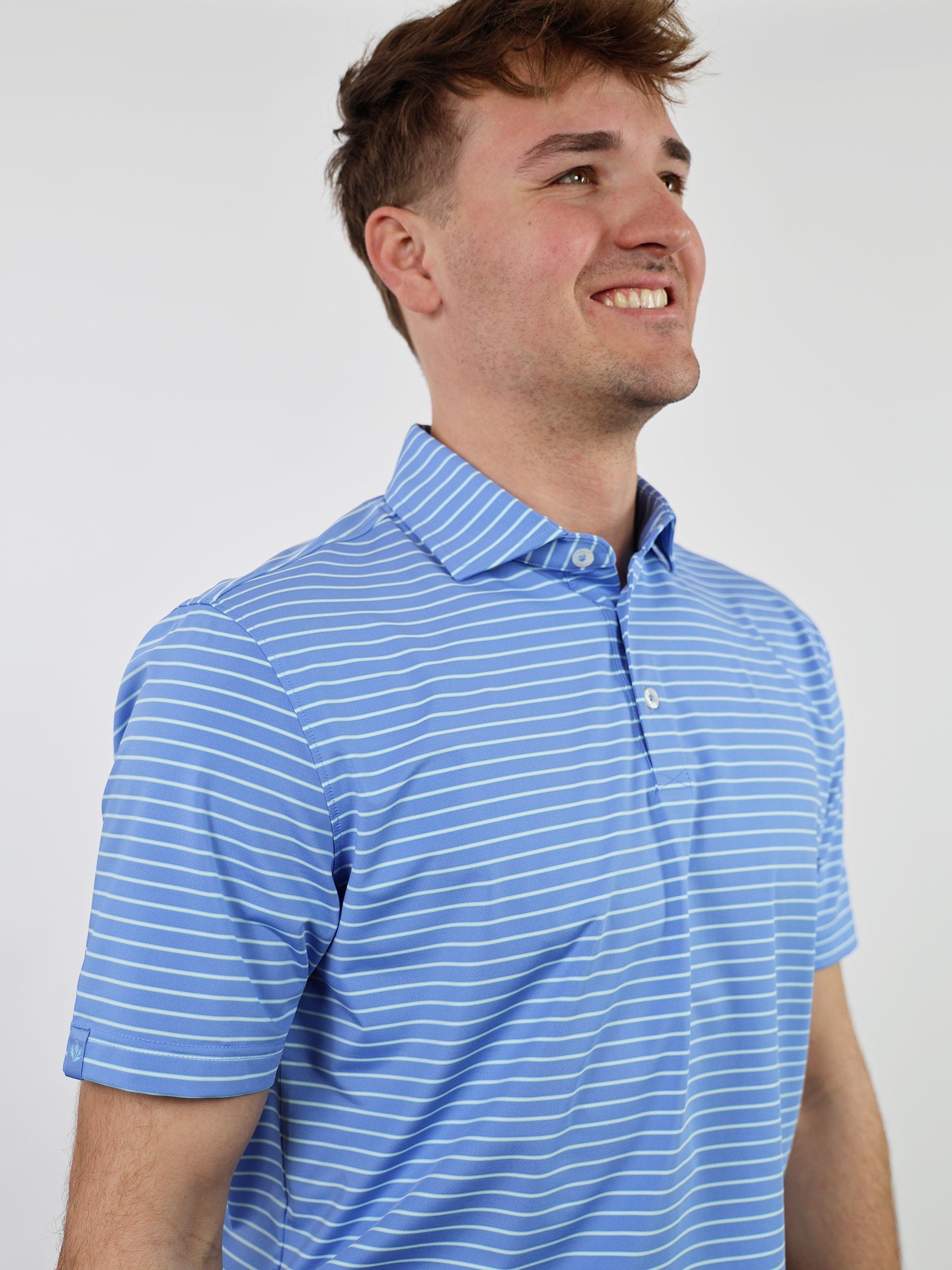 Smiling man wearing a blue and white striped polo shirt against a plain white background