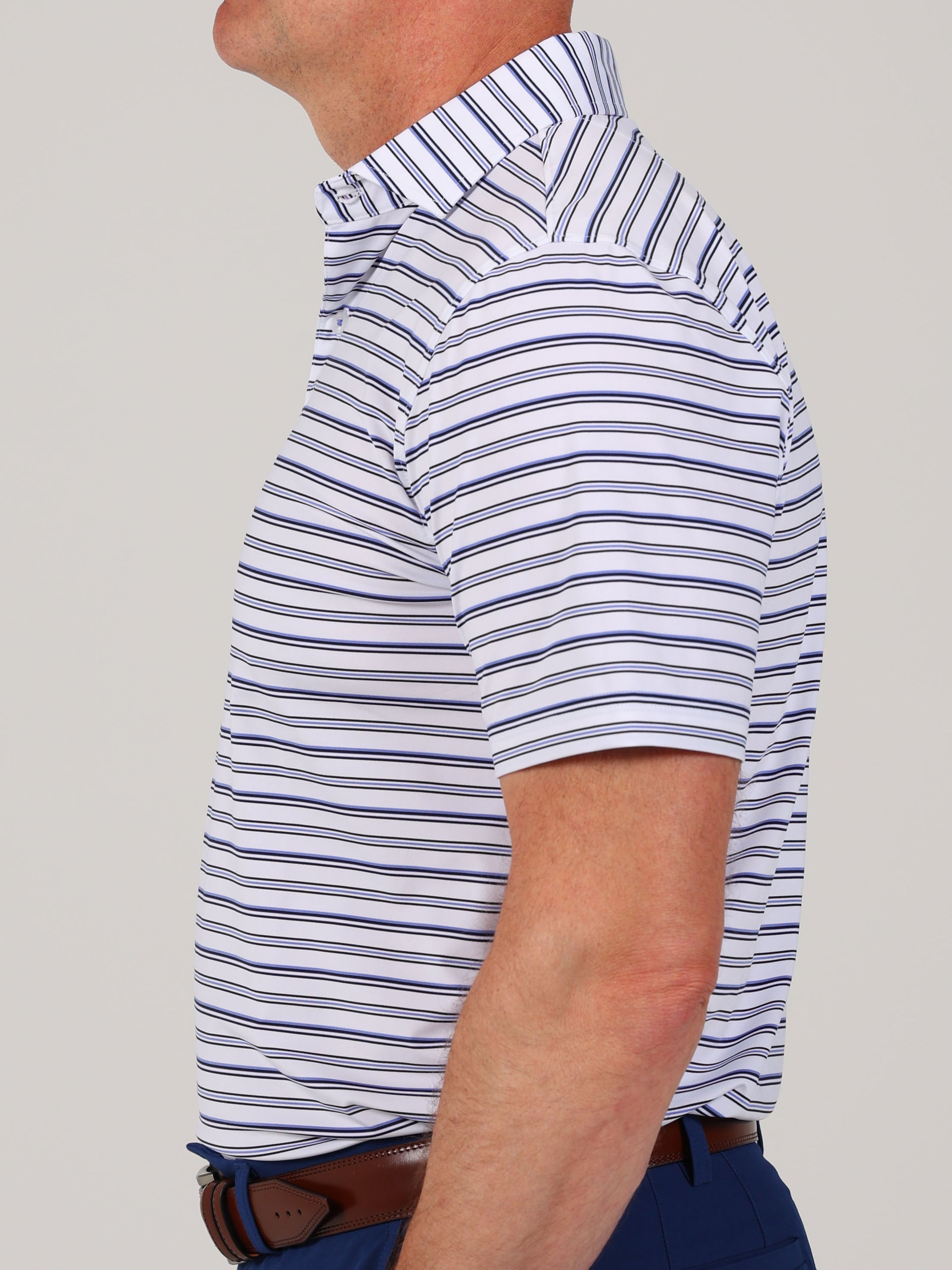 A person in a side profile is wearing a white shirt with thin navy stripes and blue pants. The pose is neutral, conveying a casual tone.