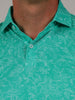 Close-up of a teal shirt with white floral patterns, emphasizing texture and button details. The collar is neatly folded, conveying a casual, fresh vibe.