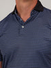 Close-up of a person wearing a polo shirt with a blue and black diamond pattern and black collar, conveying a casual and stylish look.