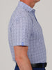 A man is shown in profile wearing a short-sleeved, light blue patterned shirt with a black belt.