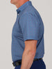 A man is standing sideways in a blue patterned shirt with short sleeves.