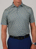 Man in a short-sleeved, light blue polo with small yellow shark patterns, paired with dark blue pants. The tone is casual and polished.