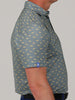 A man is shown from the side wearing a blue shirt with a yellow shark print pattern. The shirt has a collar and short sleeves, conveying a casual style.