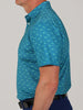 Man in a teal, short-sleeved shirt with a small shark pattern, seen from the side. The shirt is paired with blue pants and a black belt.