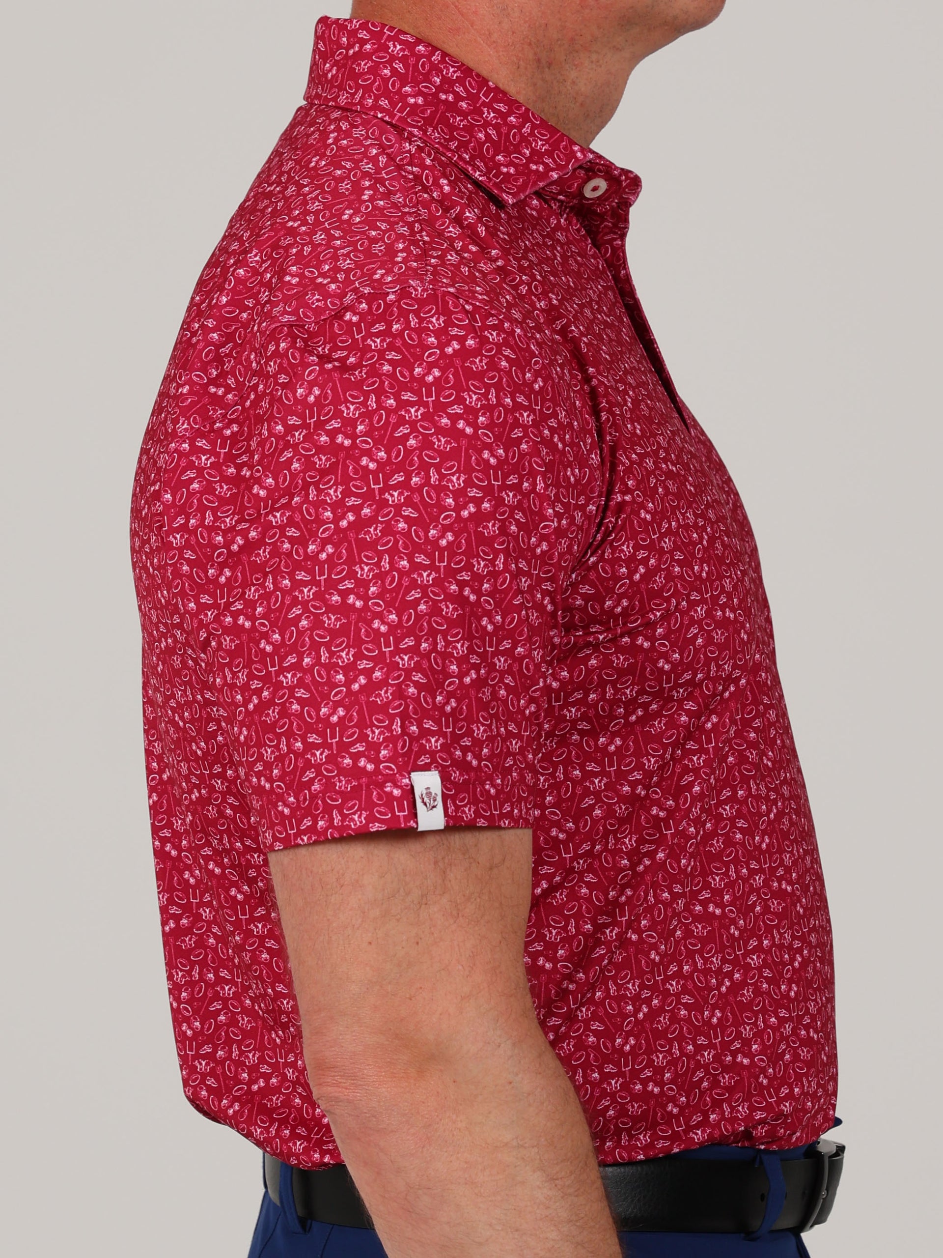 Side profile of a person wearing a vibrant red short-sleeve shirt with a white football pattern.