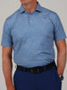Man wearing a blue, camoflauge patterned short-sleeve polo shirt and dark blue pants. He has a black belt and a silver wristwatch. The background is plain gray.