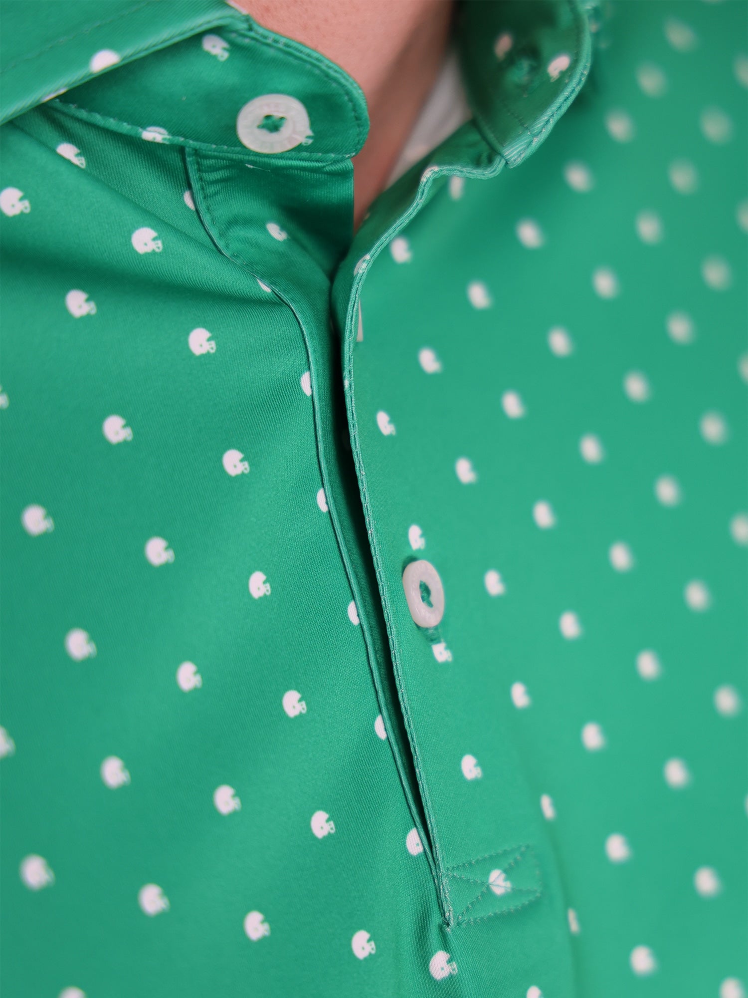 Close up of man wearing a green golf polo showcasing its pattern of white football helmets