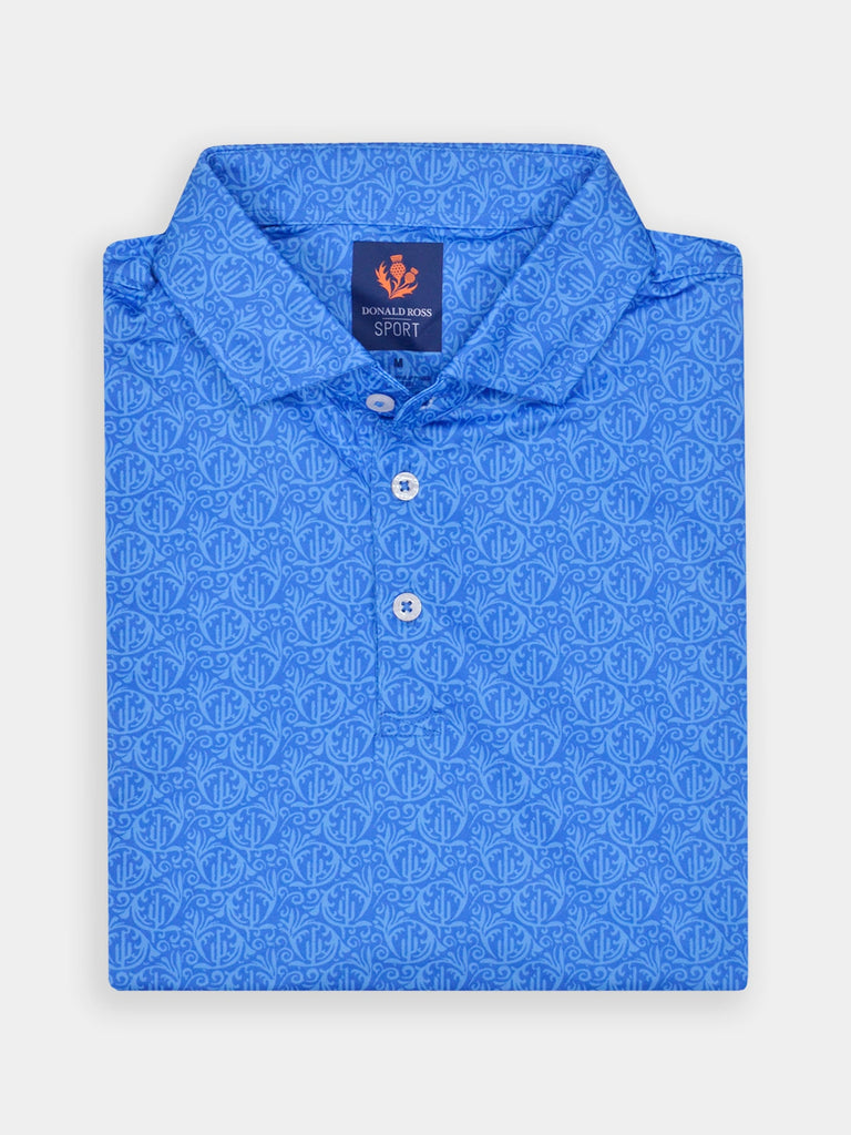 Folded blue polo shirt with an intricate geometric pattern. The shirt features a button-down front and an inside label