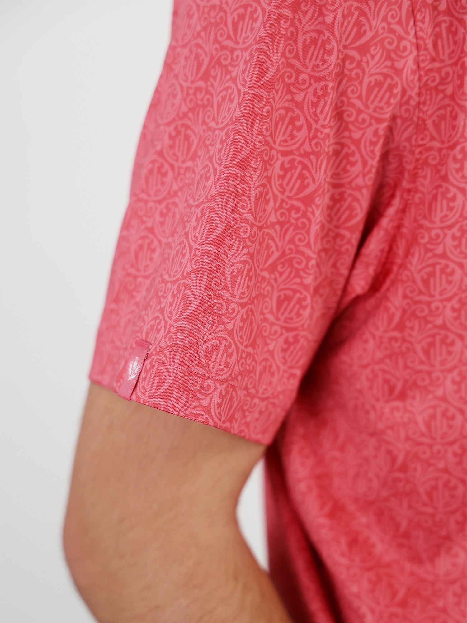 Close-up of a person wearing a red short-sleeved shirt with an intricate circular pattern