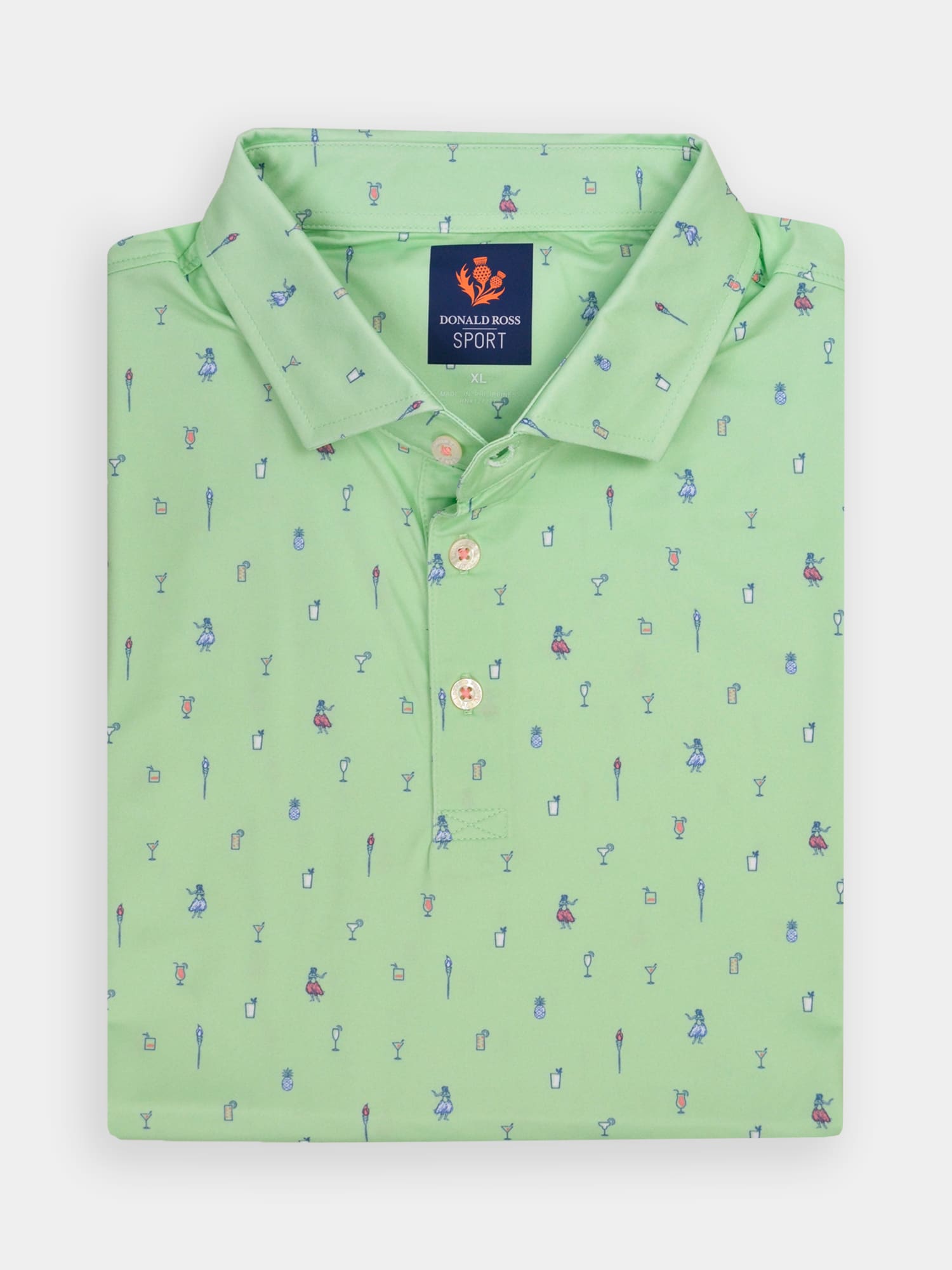 Folded green polo shirt decorated with tiny hula dancer illustrations, colorful drinks, and tropical elements