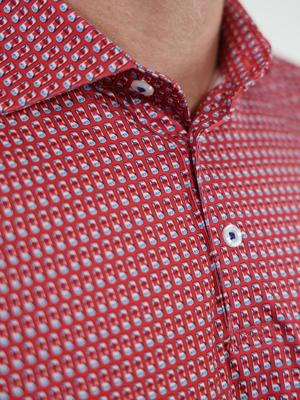 Close-up of a red shirt with a pattern of small beer cans in blue and red