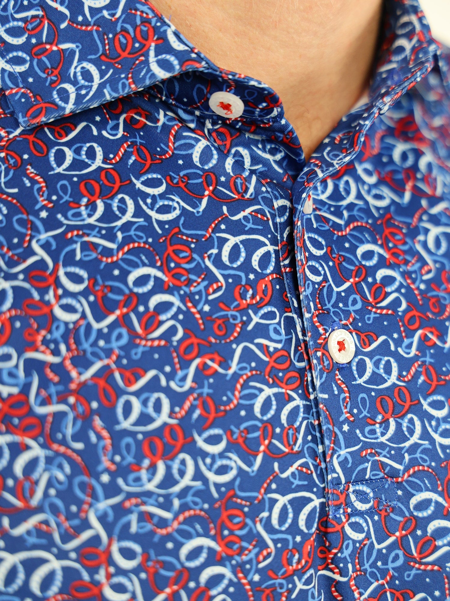 Close-up of a blue shirt with a vibrant pattern of red and white swirls and loops
