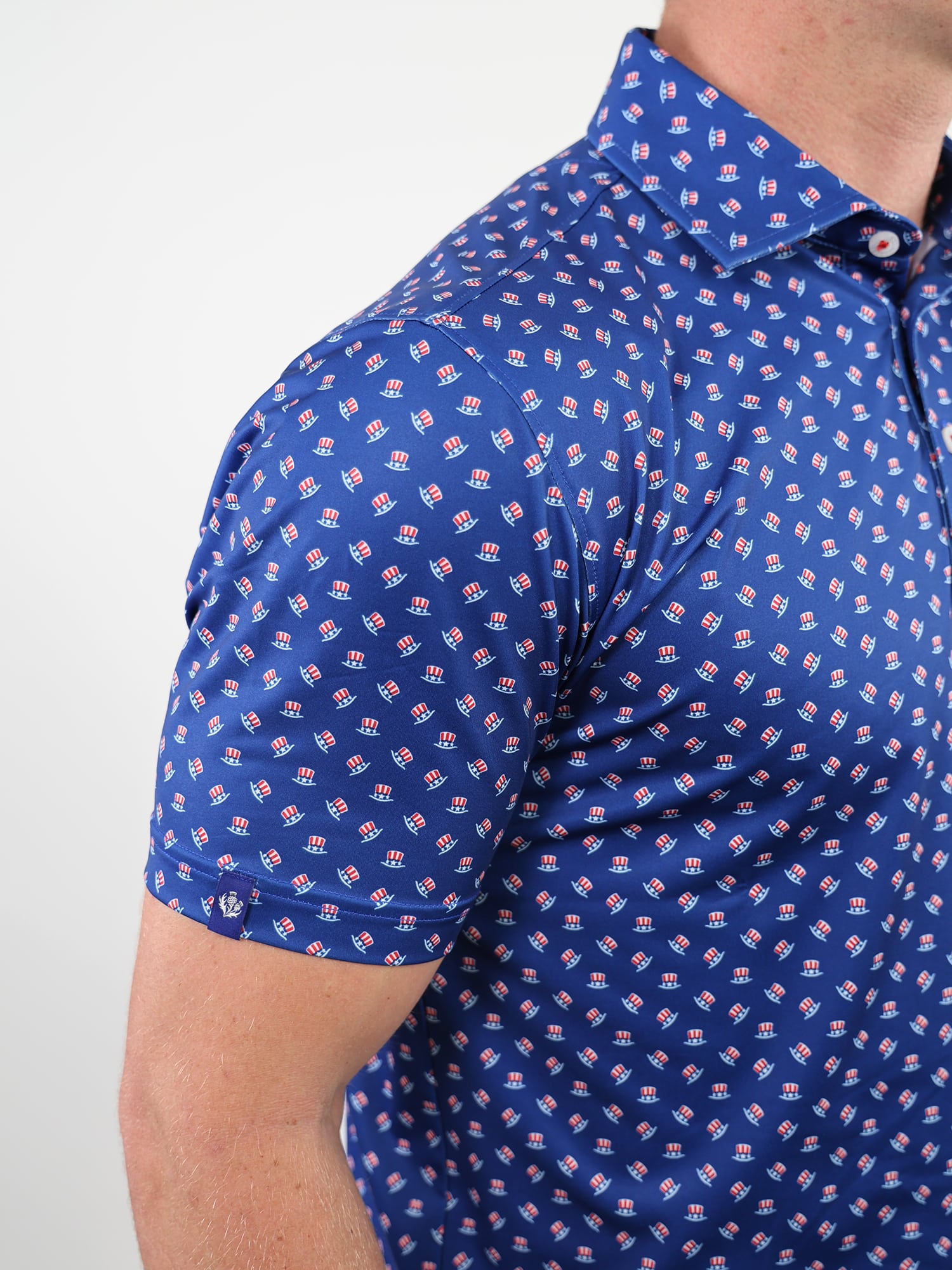 Man wearing a blue polo shirt with a pattern of uncle sam hats
