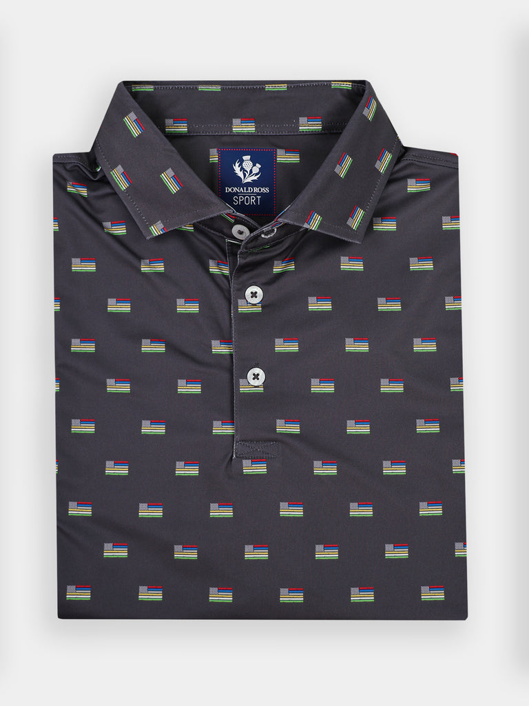 Folded dark polo shirt featuring a pattern of small American flags with rainbow stripes
