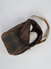 Plaid bag with a partially open zipper reveals white sneakers inside. The bag features tan handles and a brown interior lining.