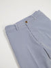 Blue and white vertically striped pants with a brown button and belt loops are laid on a white surface. The crisp lines convey a casual yet sharp look.