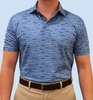 A person is standing in a blue shirt with a boat pattern, wearing khaki pants and a brown belt against a light blue background.