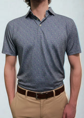 A person wearing a patterned short-sleeve polo shirt and tan pants stands with arms relaxed at their sides.